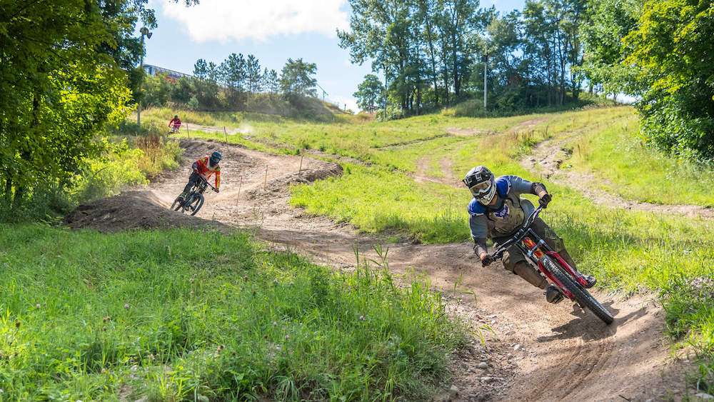Mountain bikers riding down flowy bermed trail at Horseshoe bike park in Ontario, Canada