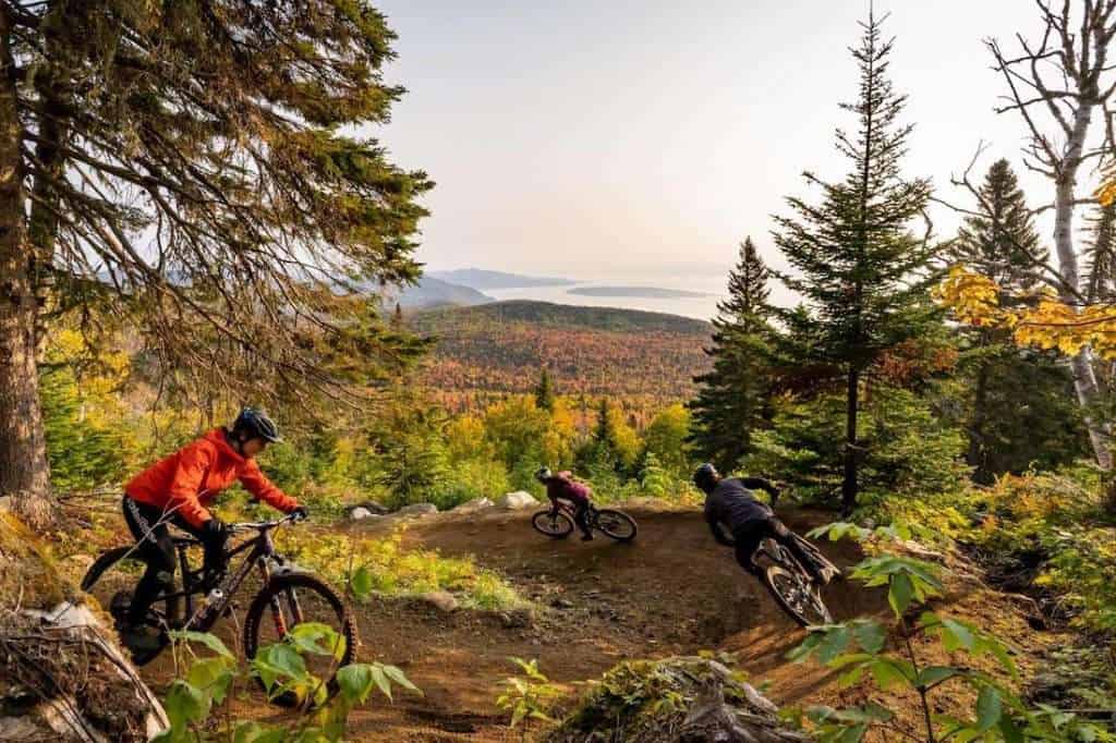 Mountain bikers riding down bermed flow trail at Le Massif Bike Park in Quebec