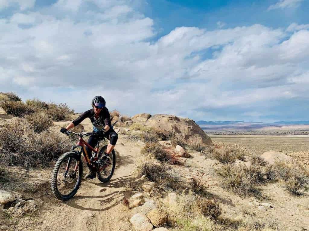 Becky on mountain biking preparing to turn around tight corner on trail in high desert of California