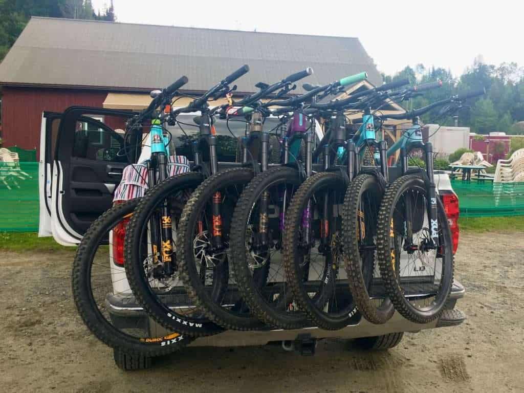 Back of pickup truck carrying seven mountain bikes with front wheels draped over tailgate