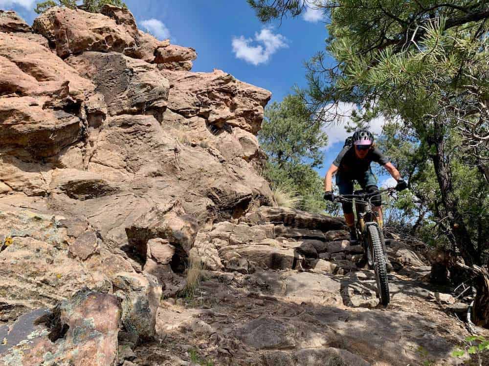 Becky on mountain bike riding down rocky and technical section on trail in Hurricane, Utah