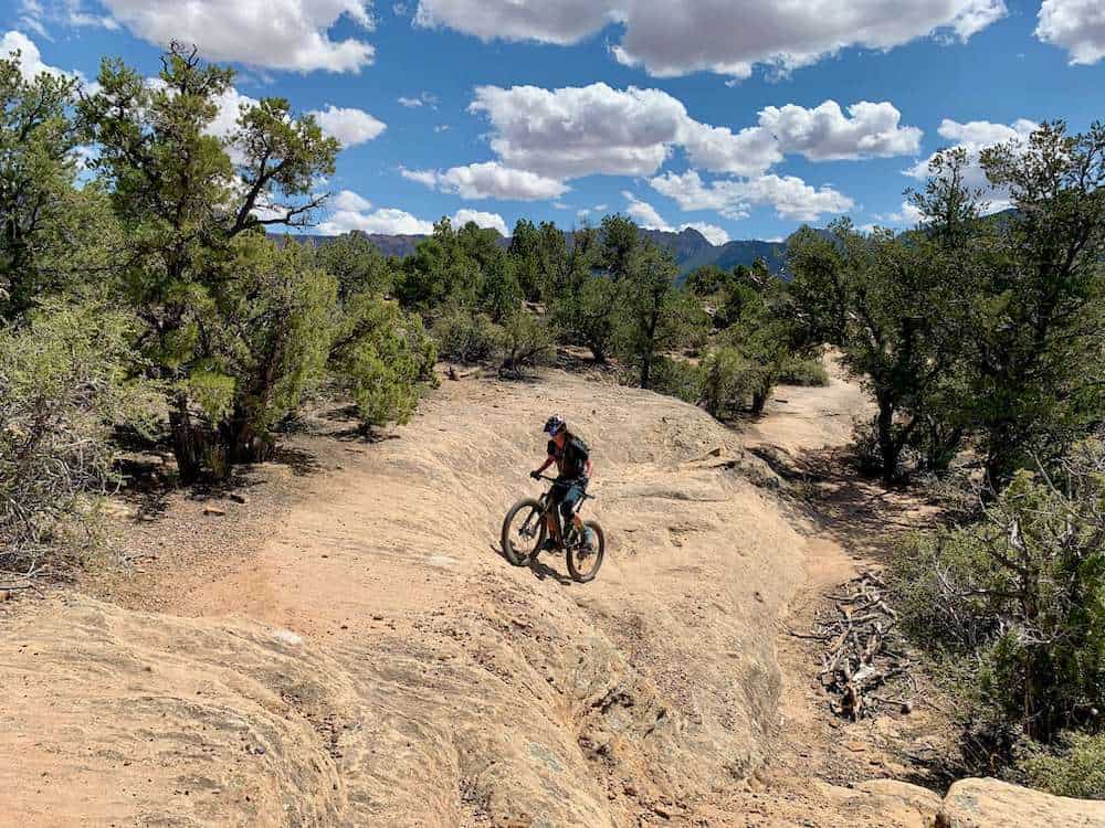 Becky riding up steep slickrock trail on mountain bike in Hurricane, Utah