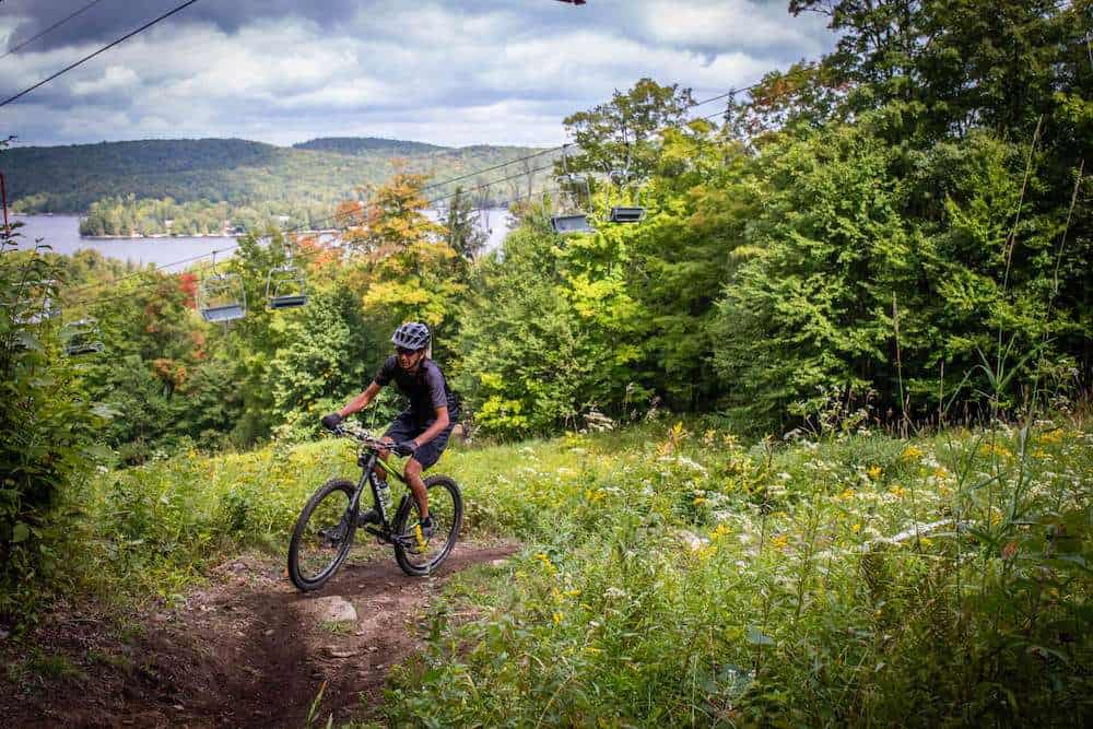 Mountain biker riding up trail at Sir Sams bike park in Ontario with lake views in background