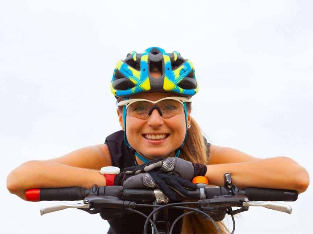 Female cyclist with arms resting on handlebars smiling for camera