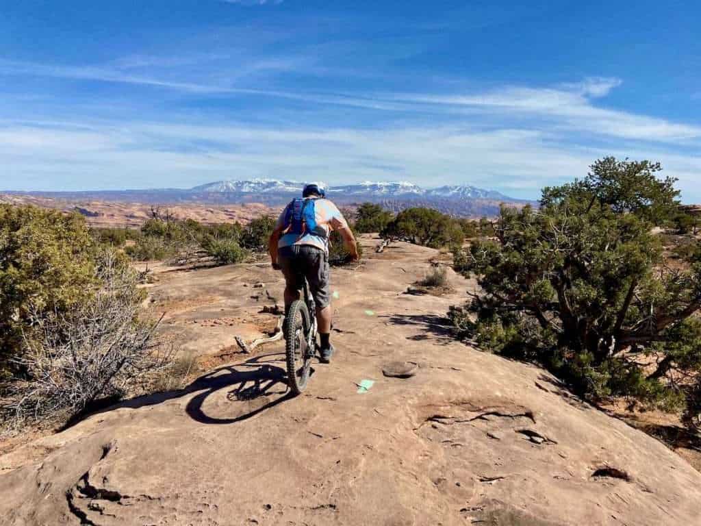Mountain biker riding away from camera on slickrock in Moab, Utah