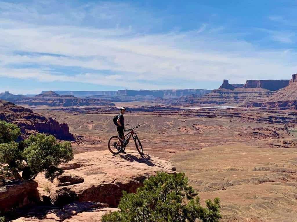 Mountain biker standing on rock overlook on Captain Ahab trail in Moab