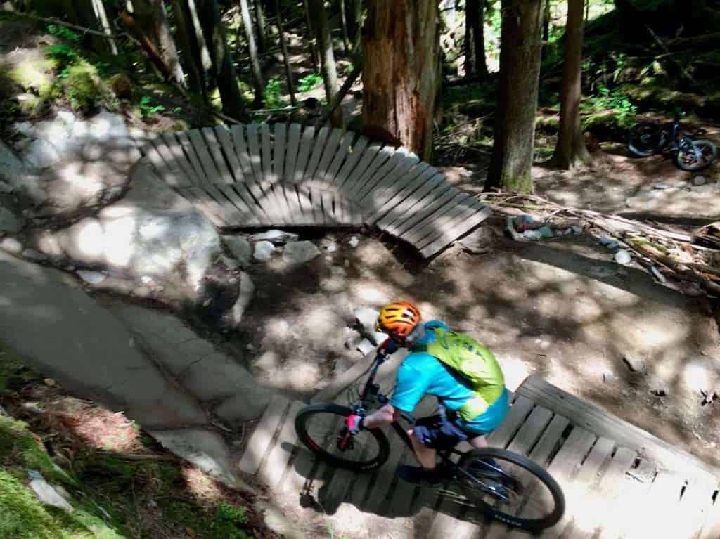 Mountain biker riding down section of trail in Squamish featuring wooden ramps and rock work