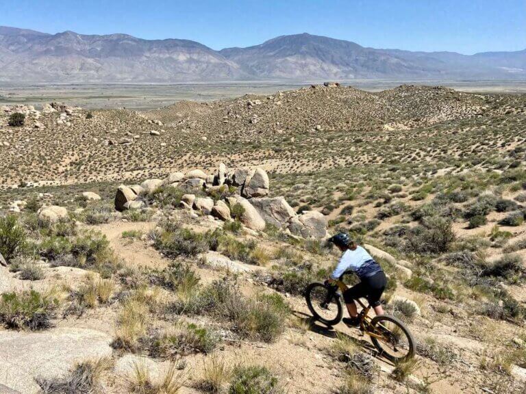 Female mountain biker riding desert singletrack wearing white mountain bike jersey