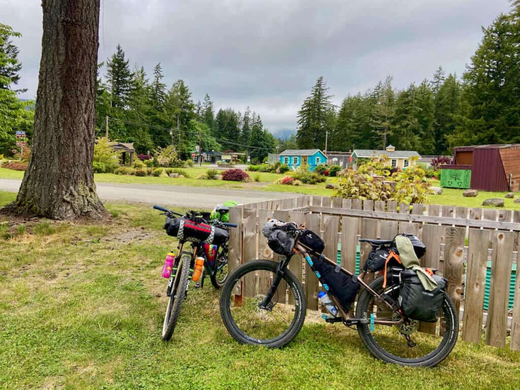 Two loaded bikepacking bikes resting against fence in Washington