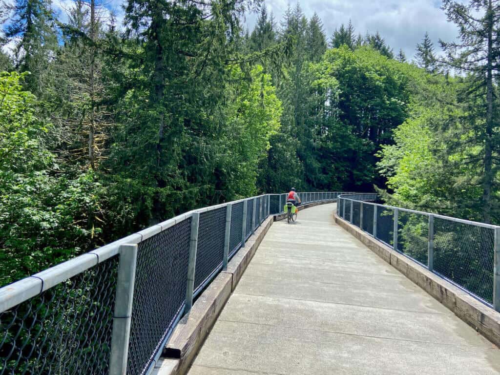 Cyclist riding over trestle bridge on rail trail to the top of Snolquamie pass in Washington