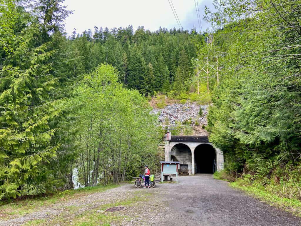Cyclist organizing gear in front of entry to three-mile tunnel on the Palouse to Cascades Trail in Washington