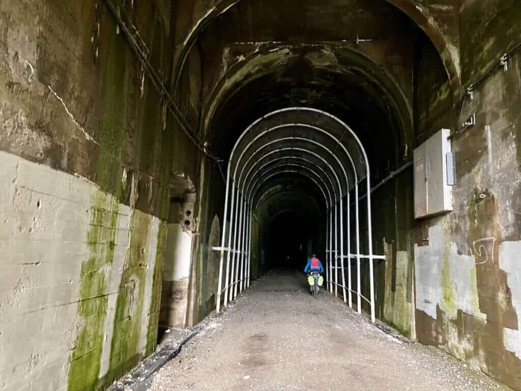 Cyclist riding through three-mile railroad tunnel that has been converted into a multi-use path