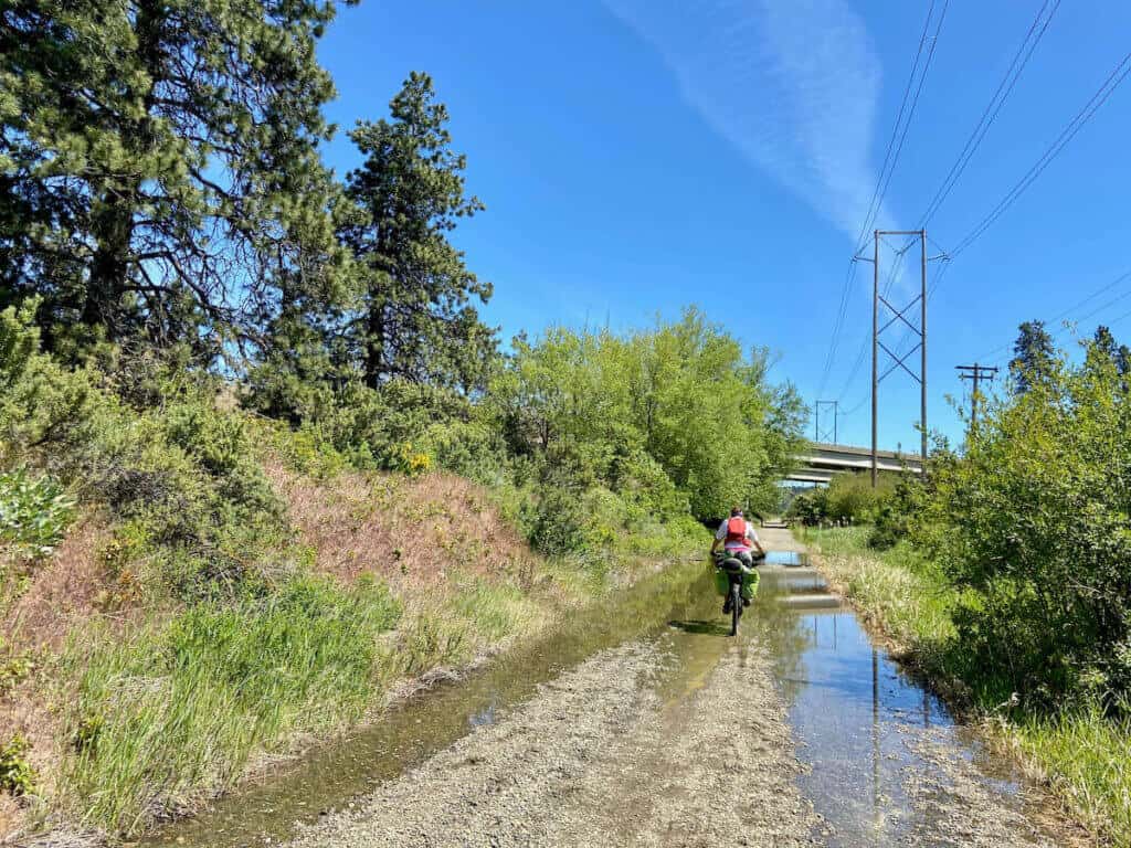 Bikepacker pedaling down slightly flooded doubletrack in eastern Washington
