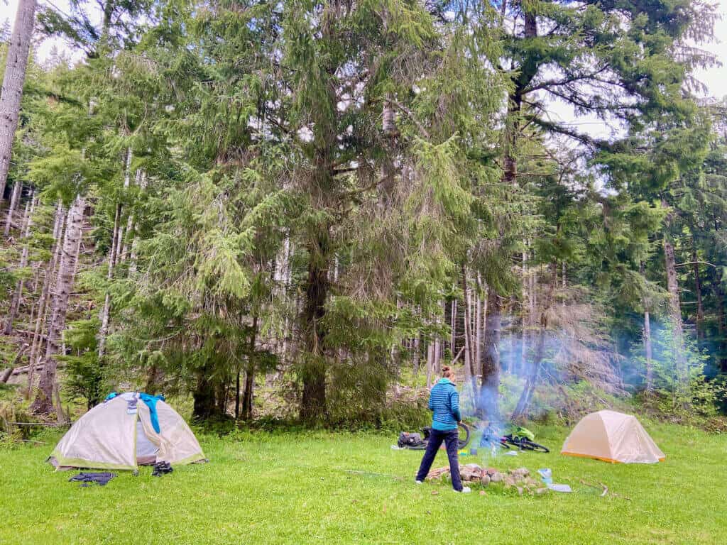 Woman standing next to smoking fire at dispersed camp on the Olympic Peninsula 