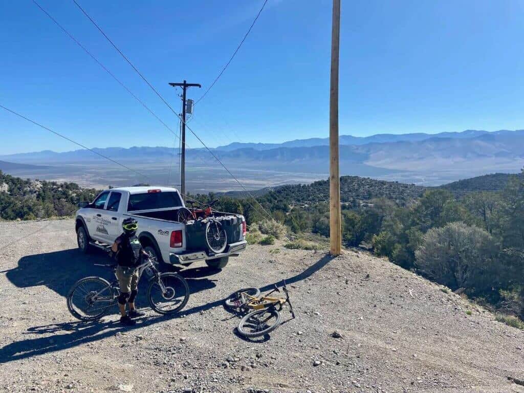 Truck parked on mountain top with mountain bikes in truck bed and lying on ground