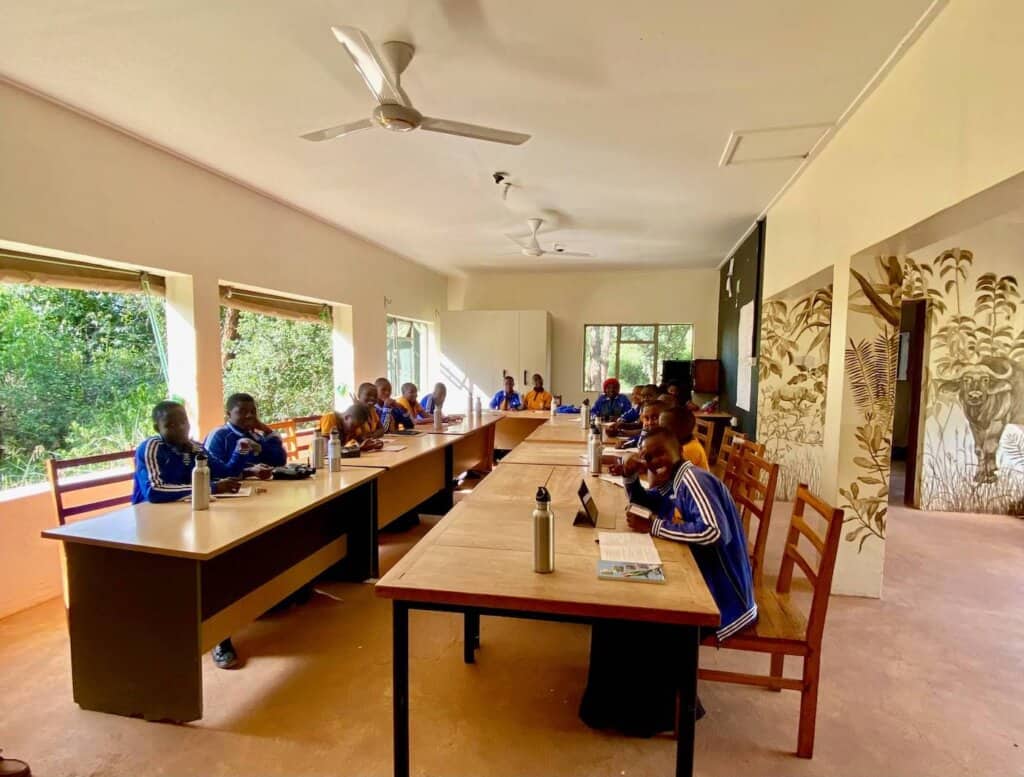 A classroom at the Environmental Education Center at the Grumeti Fund in Tanzania with students sitting at two long desks