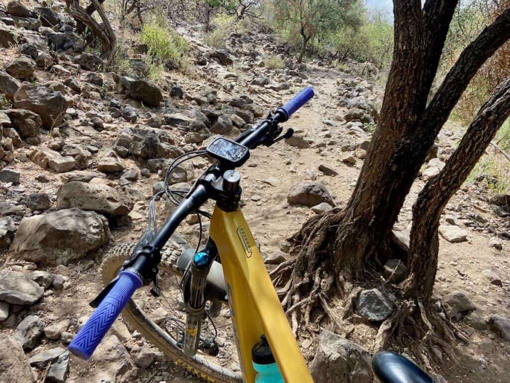 Photo out over front of mountain bike handlebars onto rocky section of trail in Tanzania, Africa