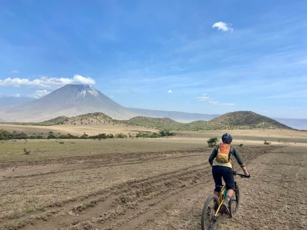 Mountain biker riding bike through open savannah in Tanzania on the K2N Stage race with volcano in the distance