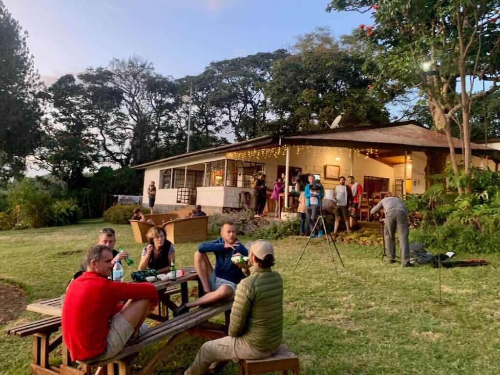 People enjoying a relaxing evening at picnic table on lawns of Simba Farm in Tanzana