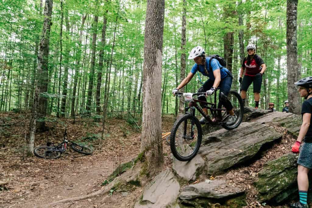 Mountain biker rolling down rock feature at Kingdom Trails in Vermont
