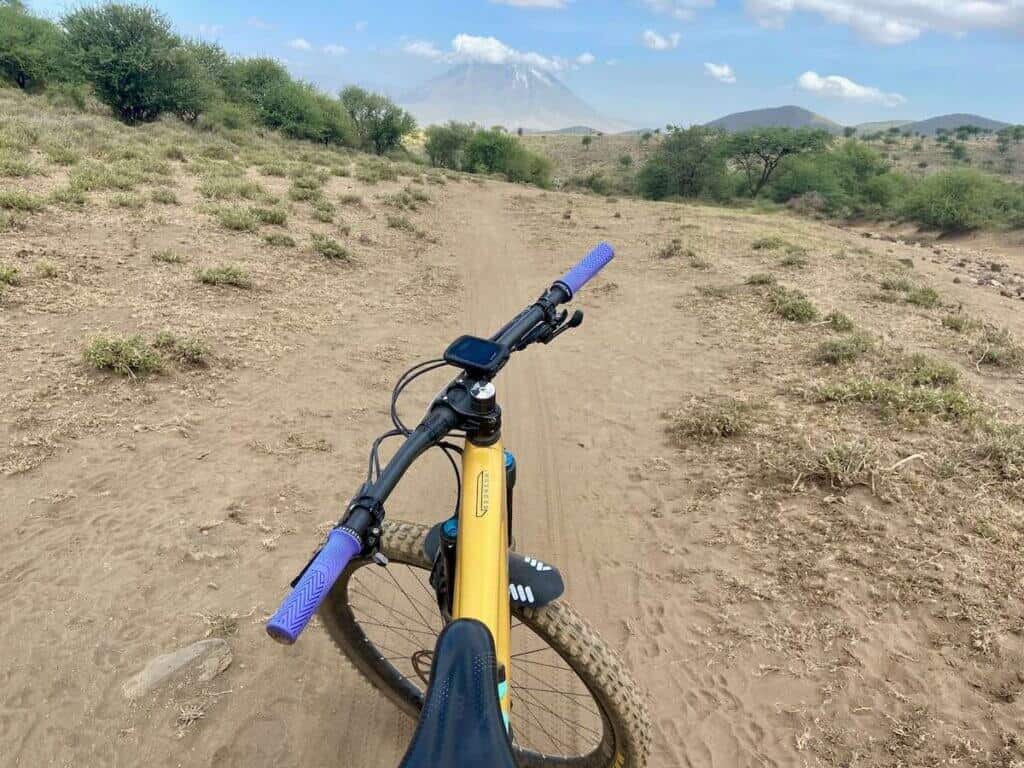Front of mountain bike with bike computer mounted on handlebars and Tanzanian volcano in background