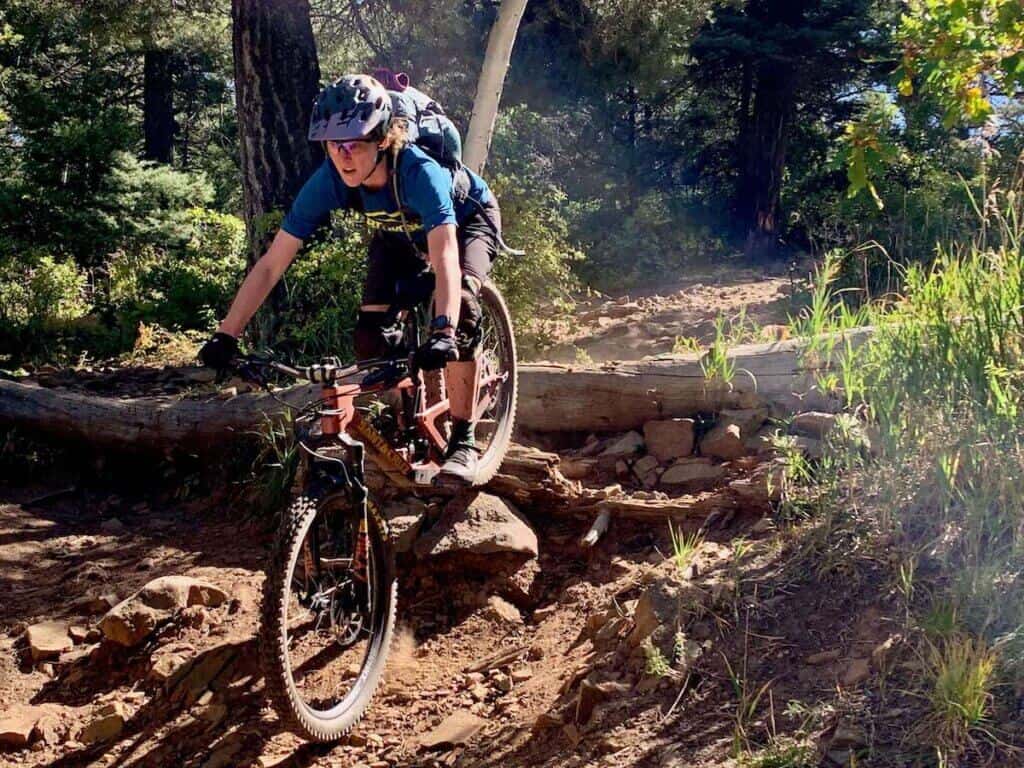 Mountain biker going over rock and log roll on technical section of trail