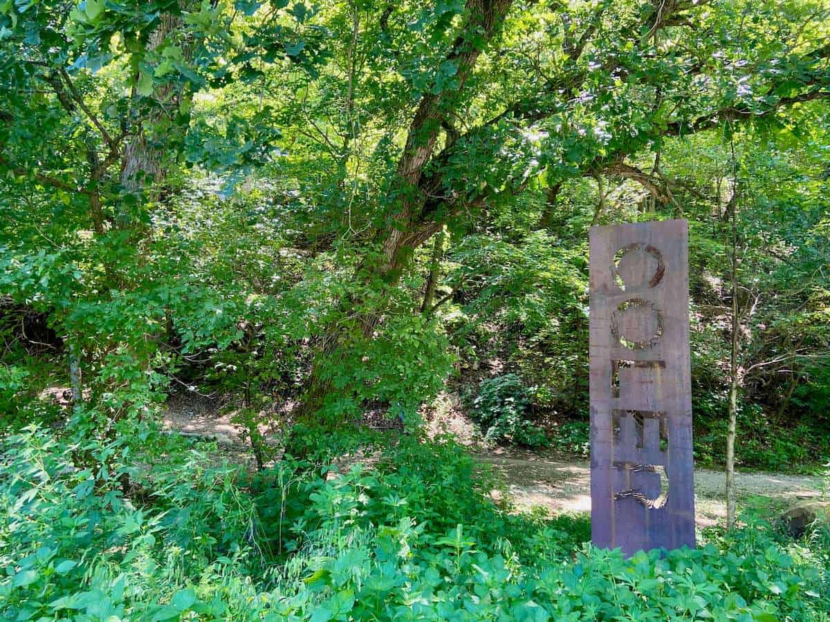 Metal vertical sign with the word "Coler" cut out at the entrance of Coler Mountain Bike Preserve in Bentonville, Arkansas