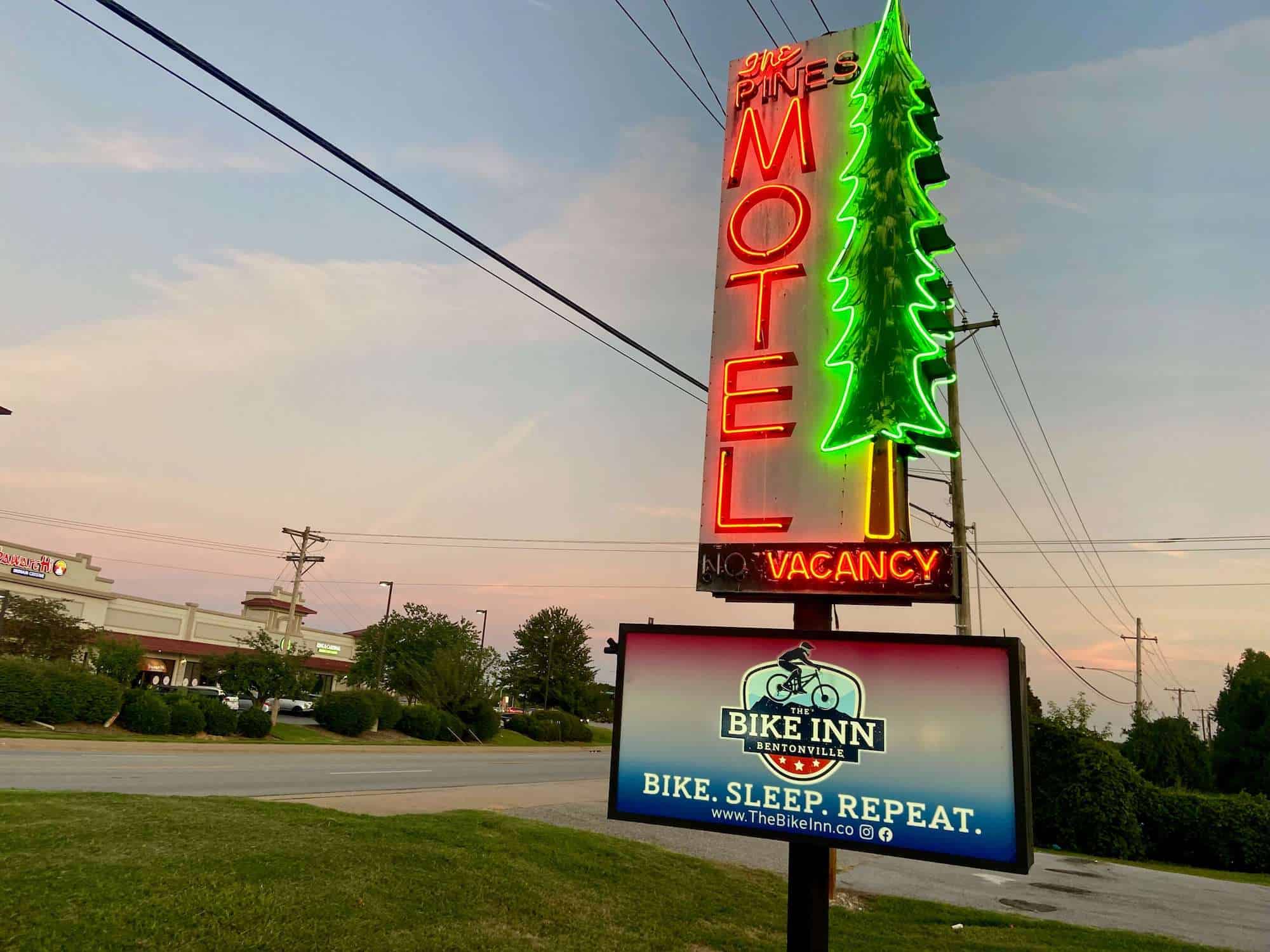 Neon motel sign with The Bike Inn Bentonville sign underneath