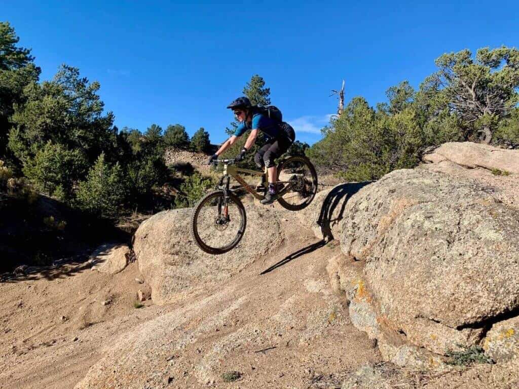 Becky riding mountain bike off rock drop in Buena Vista, Colorado