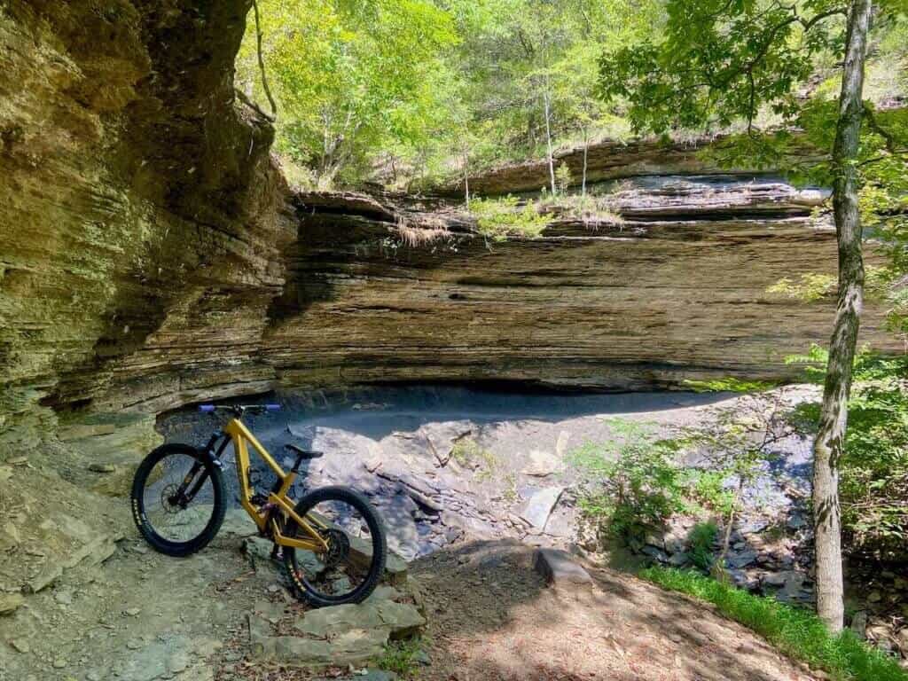 Mountain bike propped up on trail in Devil's Den State Park in Arkansas with bowl-like rock band overhang in background