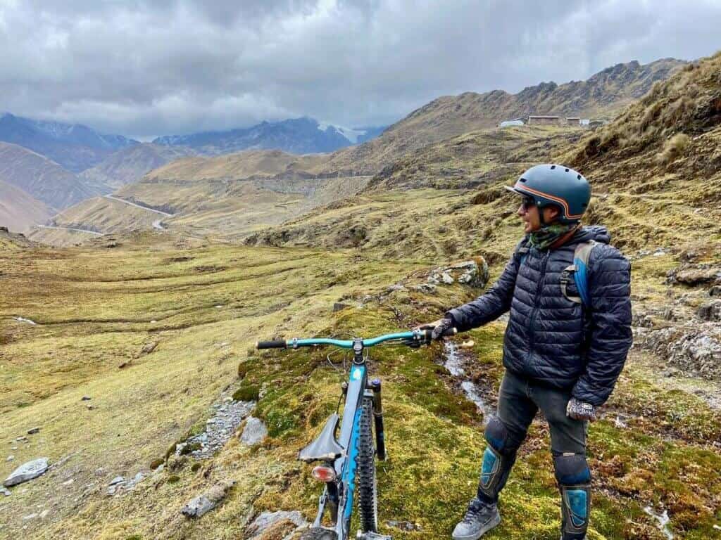 Mountain biker standing next to bike looking out over dramatic valley in Andes of Peru
