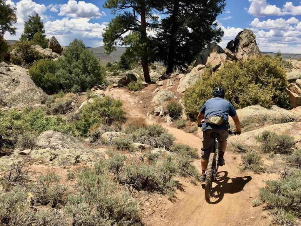 Mountain biker riding away from camera on singletrack trail at Hartman Rocks in Colorado