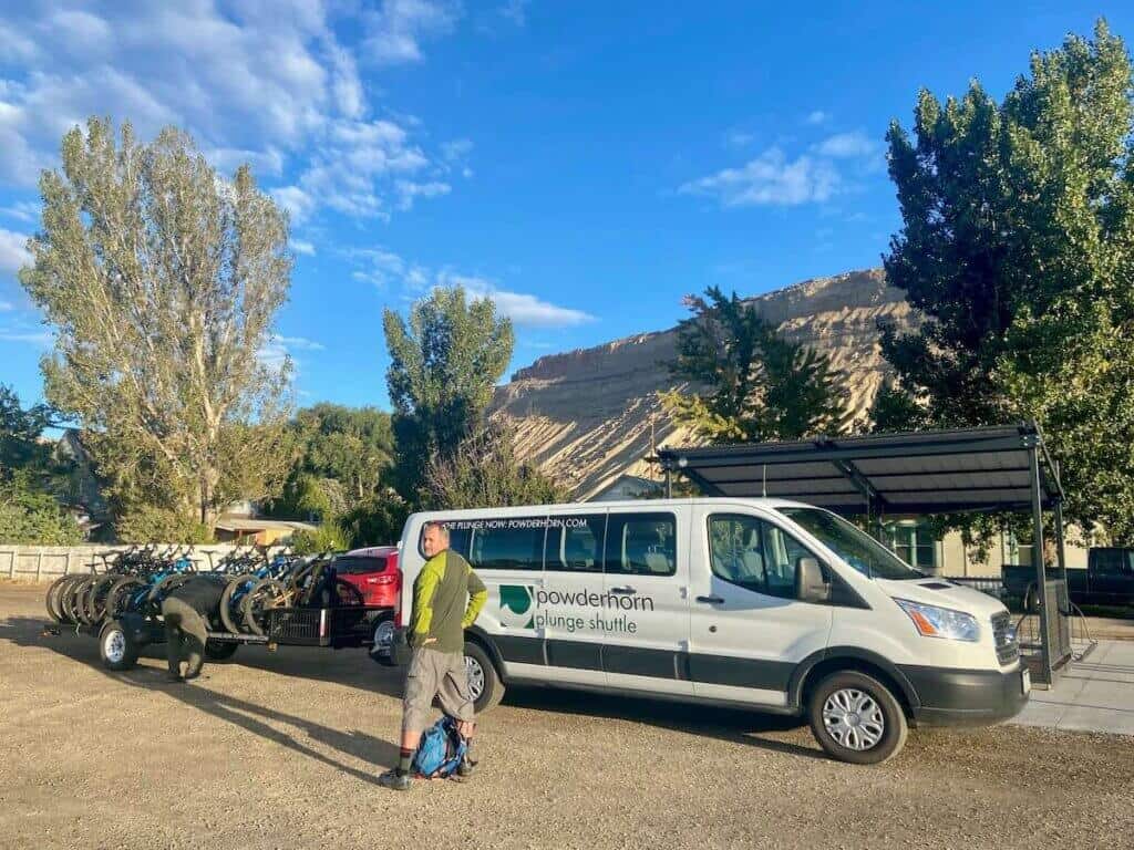 Mountain biker standing in front of shuttle bus waiting for shuttle up Palisade Plunge in Colorado