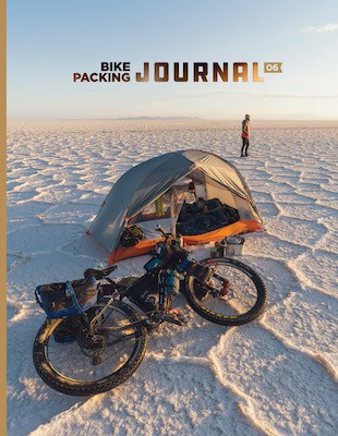 Bikepacking journal cover with bike and tent lying on salt flats
