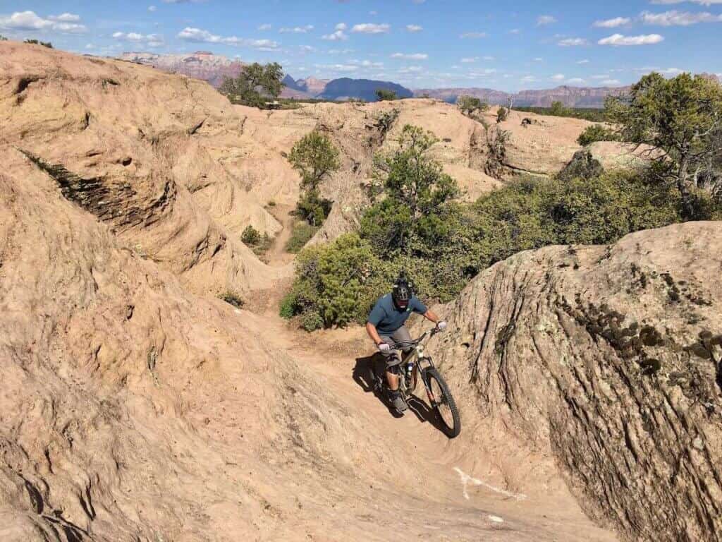 Mountain biker riding up steep, narrow slickrock shoot on Gooseberry Mesa in Utah