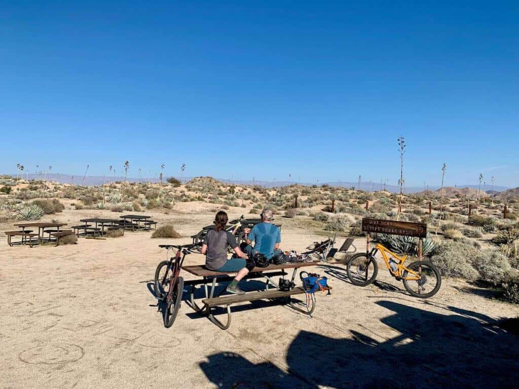 Two mountain bikers taking a break at a picnic table on desert ride in California
