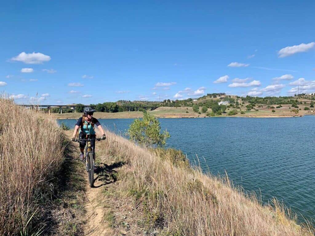 Mountain biker riding on lakeside trail in switchgrass trail network in Kansas