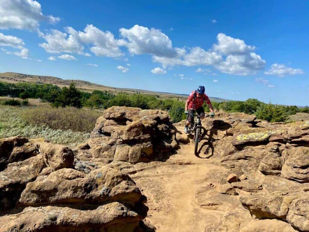 Mountain biker riding on technical rocky section of trail in Switchgrass trail network in Kansas