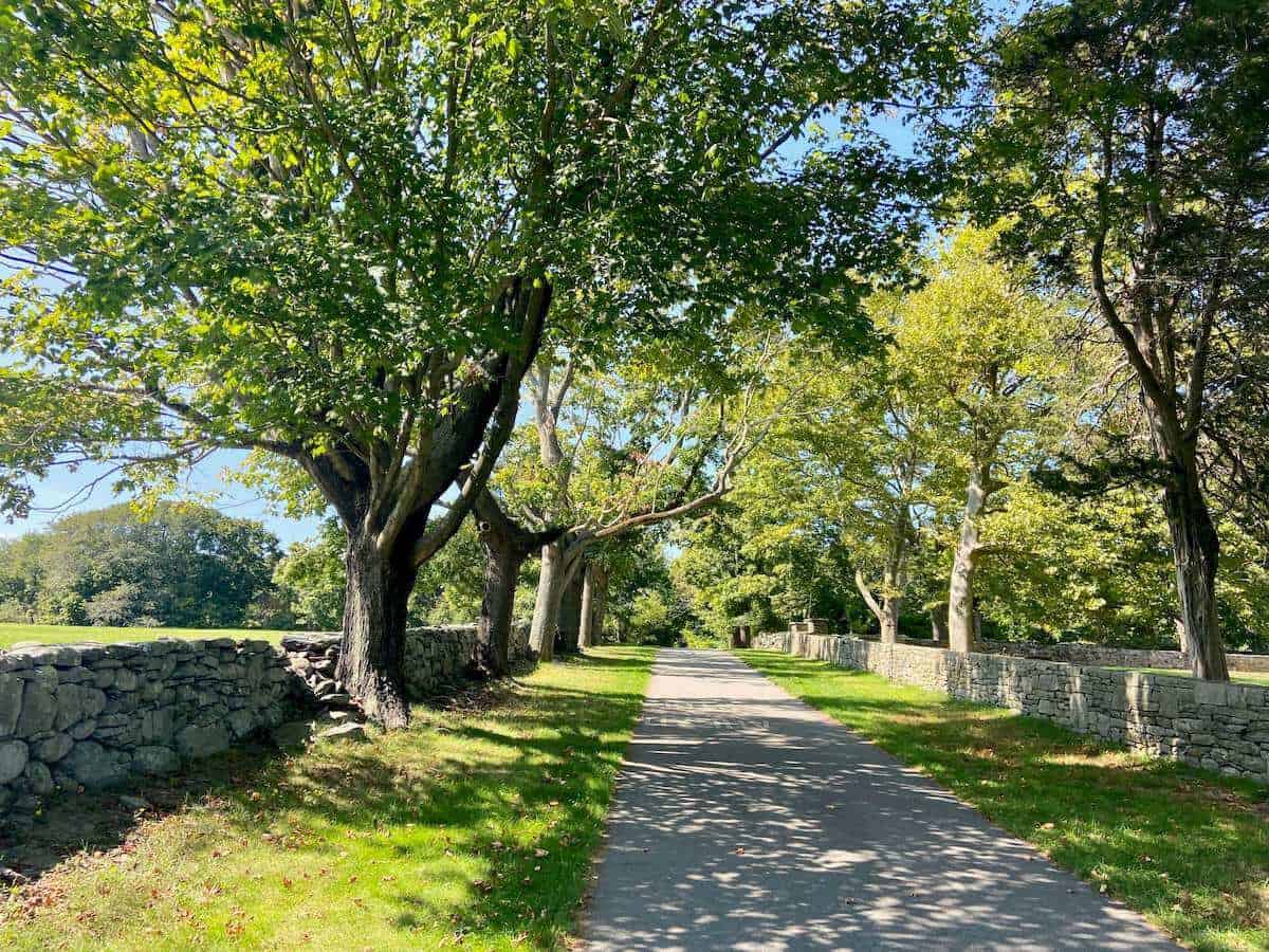 East Bay Bike path in Rhode Island with stone walls and trees lining paved path