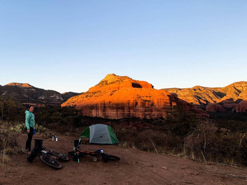 Bikepacker setting up camp as sun sets over red rocks of Sedona
