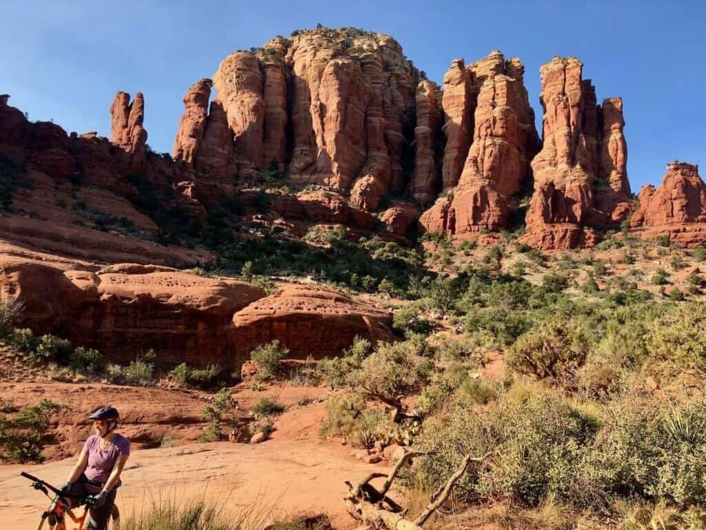 Mountain biker with bike standing in front of towering red rock formations in Sedona, Arizona