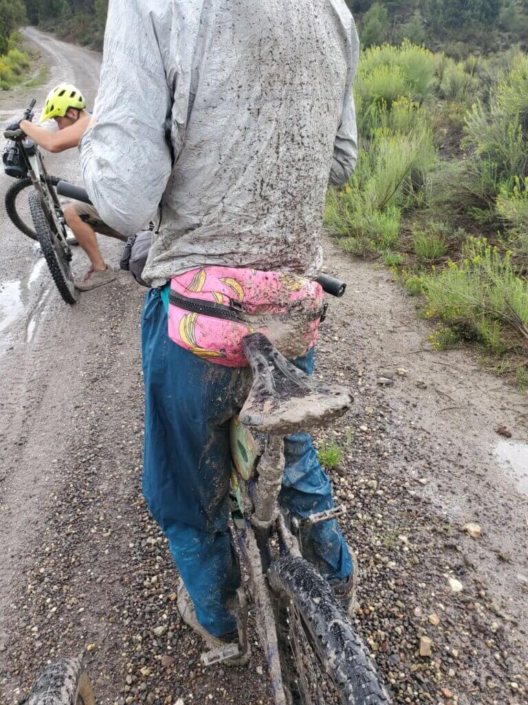 Backside of mountain biker and bike covered in mud after wet ride on road