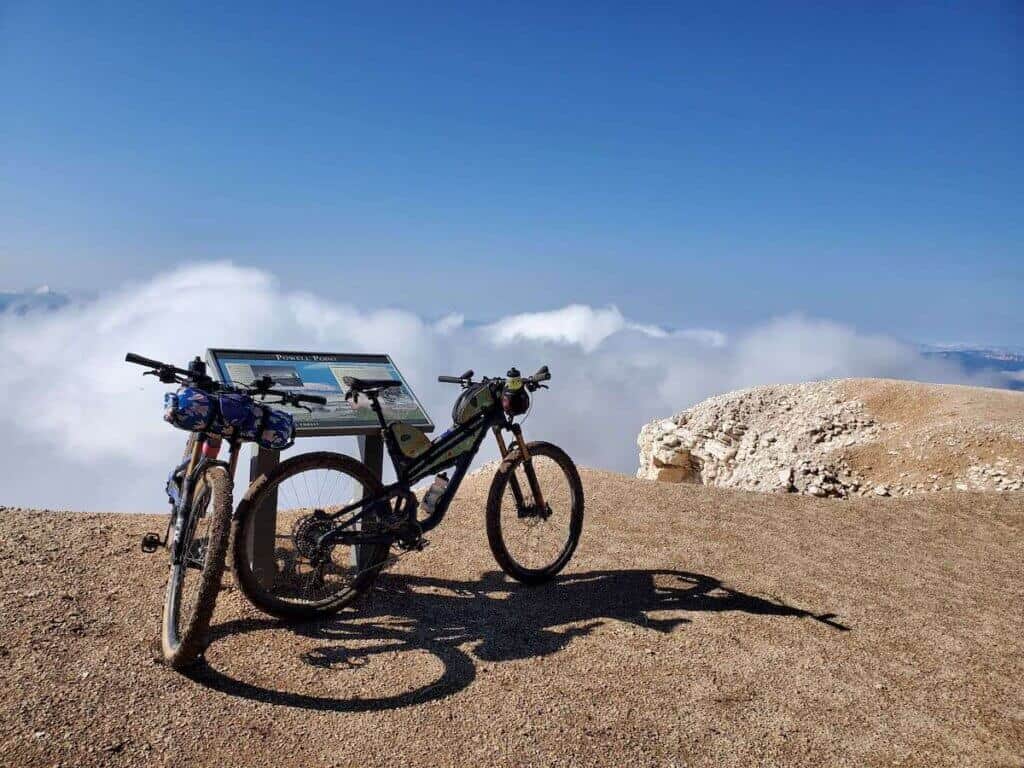 Two loaded bikepacking bikes leaning against information plaque at Powell Point lookout in Utah 