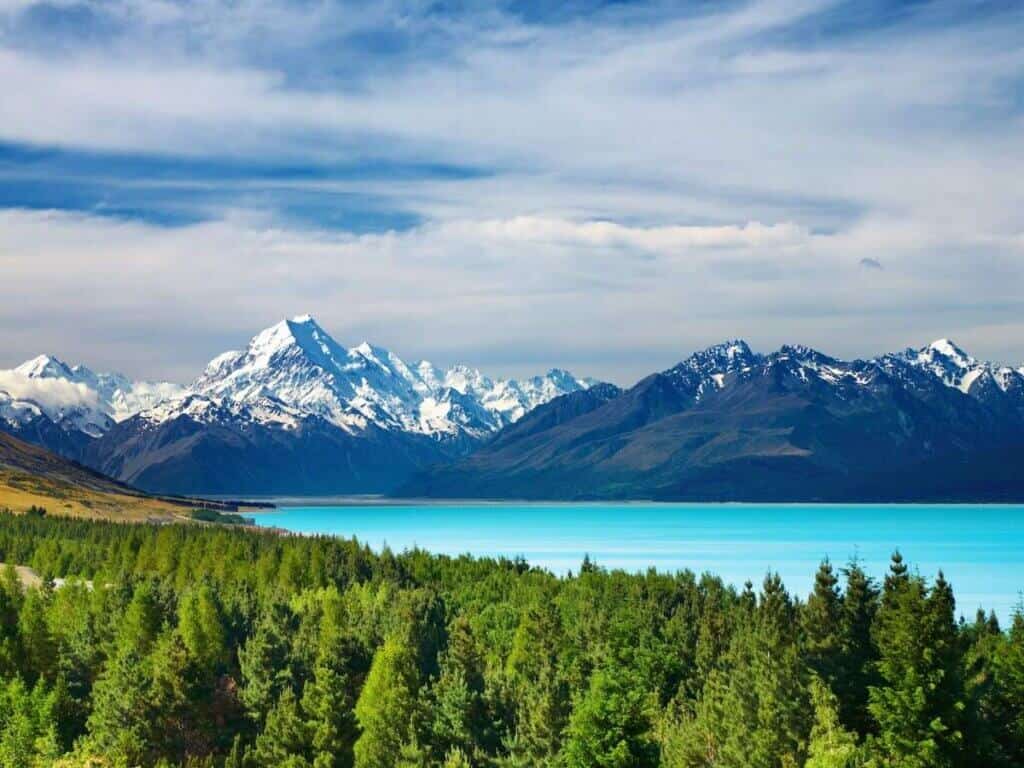 Stunning landscape views out over snow-capped peaks and blue glacial lake on South Island of New Zealand
