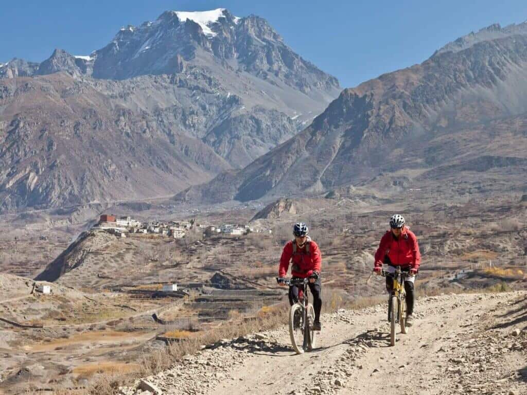 Two mountain bikers on rugged dirt road in remote area of Nepal