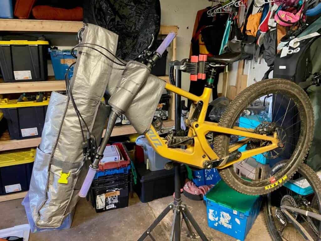 Mountain bike on bike stand with handlebars secured to the side and bike bag sleeve over front fork