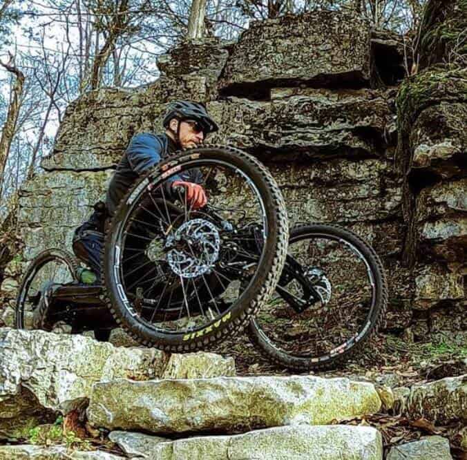 Jeremy McGhee riding adaptive mountain bike on rock ledge