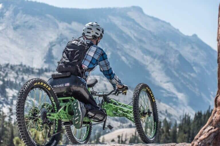 Adaptive Mountain biker riding trail with tall mountains in background