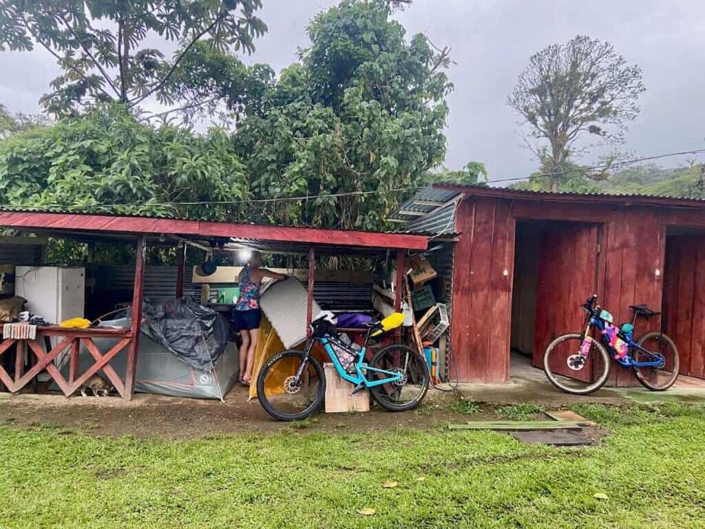 Bikepackers setting up tents under shed to stay dry from rain in Costa Rica