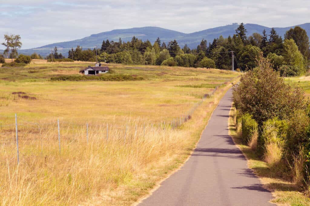 Paved Olympic Discovery Trail near Sequim Washington with dry field on lefthand side
